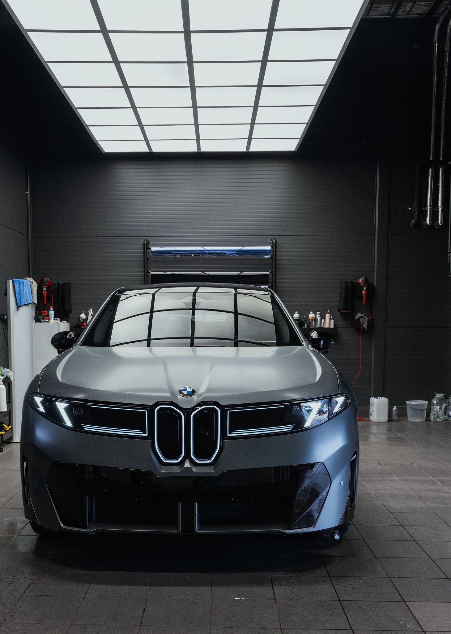 BMW iX3 i matt grå, sett rett forfra inne i studioet