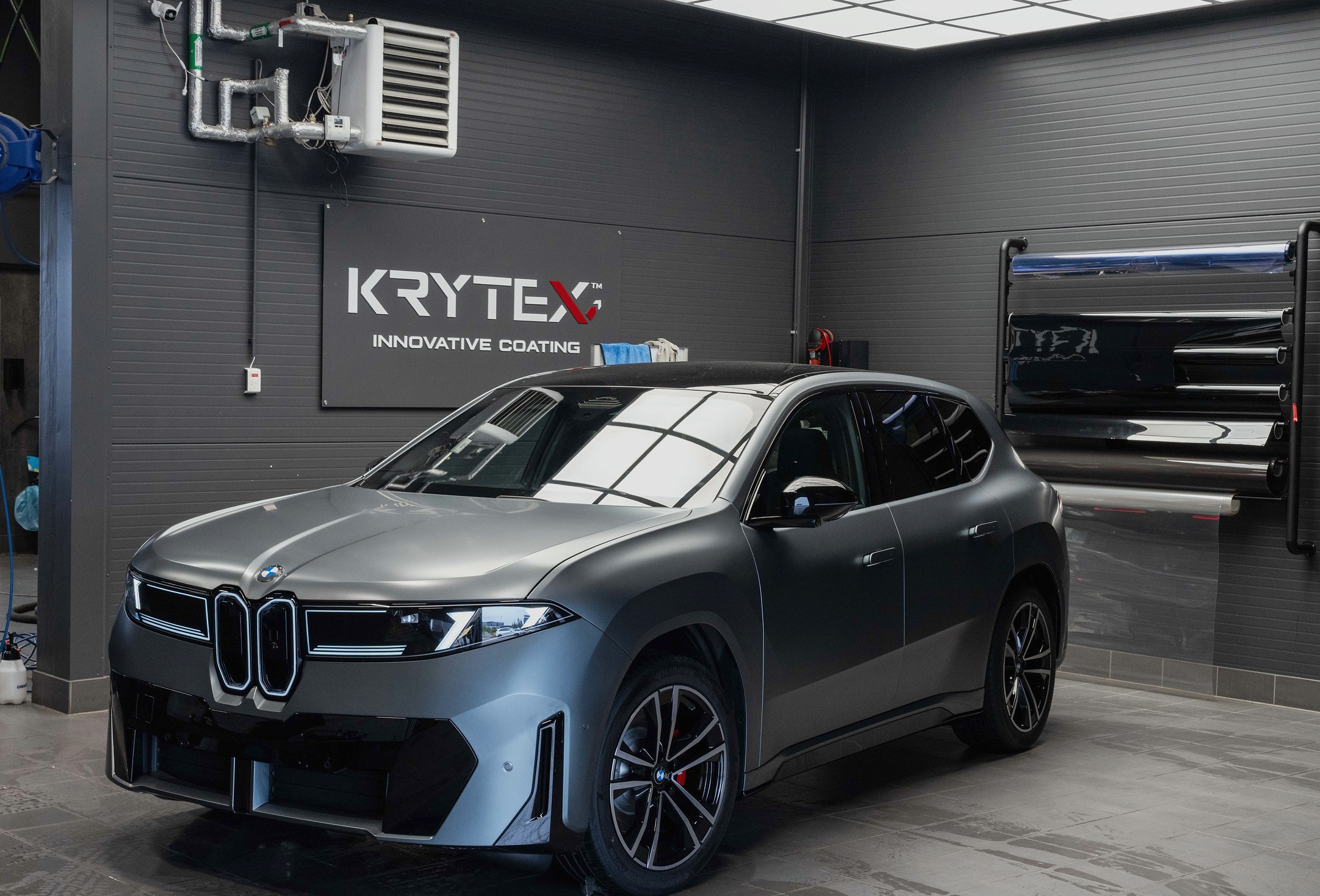 BMW iX3 i matt grå, sett skrått forfra inne i studioet