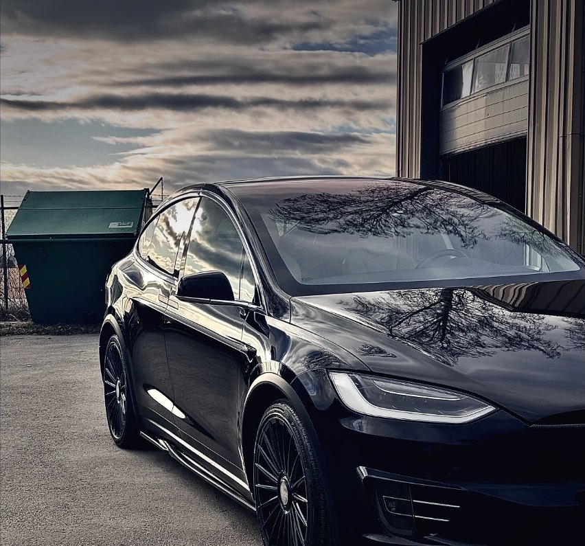 Sort Tesla Model X utenfor verkstedet i skumring
